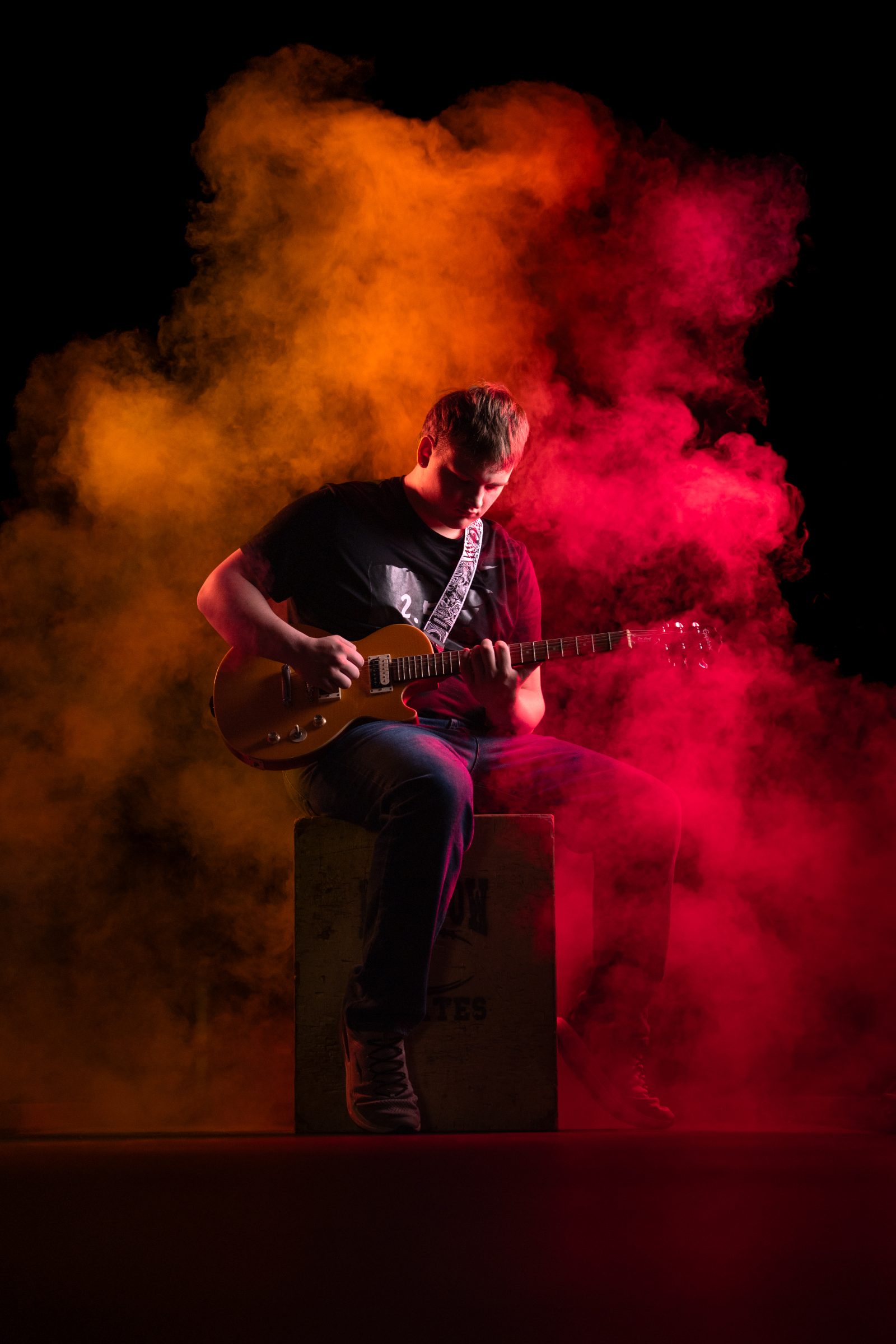 Senior playing guitar in orange and red smoke